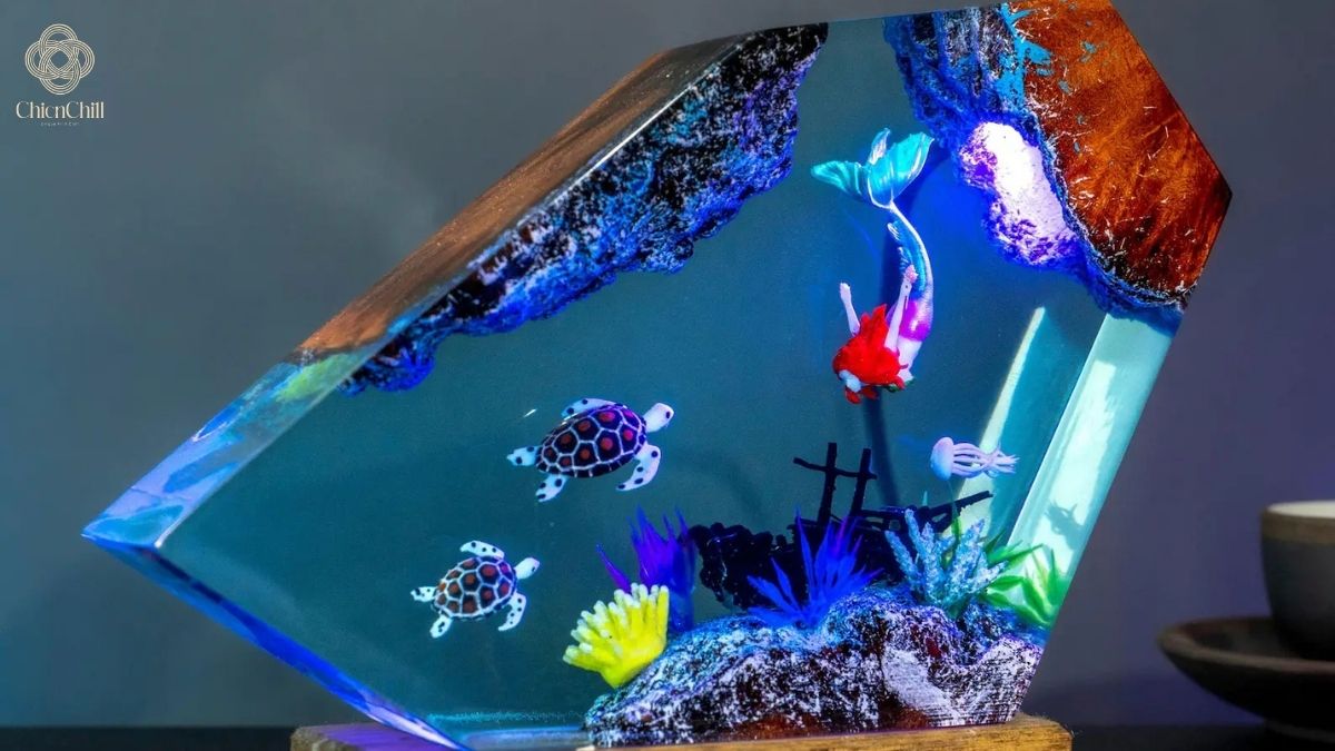 A detailed handmade resin night light on a wooden base featuring a mermaid, sea turtles, and a coral reef suspended in clear blue epoxy.